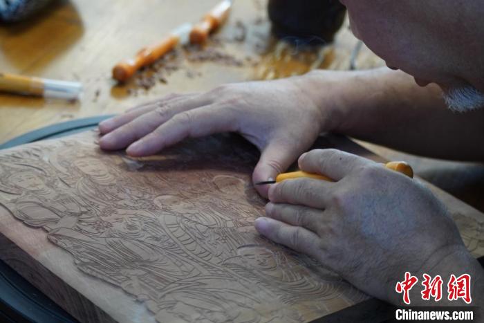 圖為徐晉林湊近木板，近距離制作雕版畫(huà)?！【琶赖┰?　攝