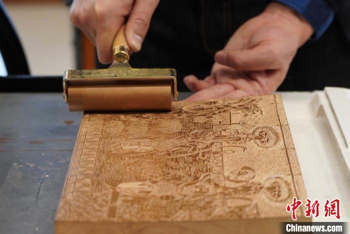 圖為徐晉林工作室工作人員正在給雕好壁畫(huà)的版面滾油墨?！【琶赖┰?　攝