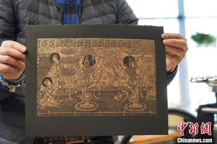 圖為手工書(shū)藝人展示敦煌雕版壁畫(huà)印刷品。　九美旦增 　攝