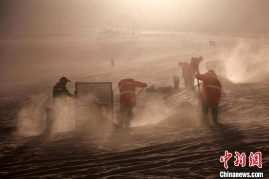 圖為敦煌市鳴沙山月牙泉景區(qū)“駱駝保姆”清理駱駝糞便?！垥粤?攝