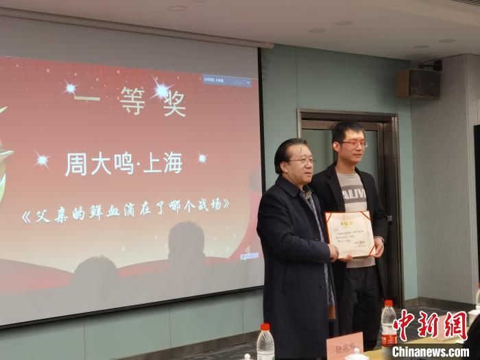 圖為作家、西北師范大學(xué)新聞與傳媒學(xué)院院長(zhǎng)徐兆壽頒發(fā)一等獎(jiǎng)證書，代領(lǐng)獎(jiǎng)?wù)呱吓_(tái)領(lǐng)獎(jiǎng)。　楊娜 攝