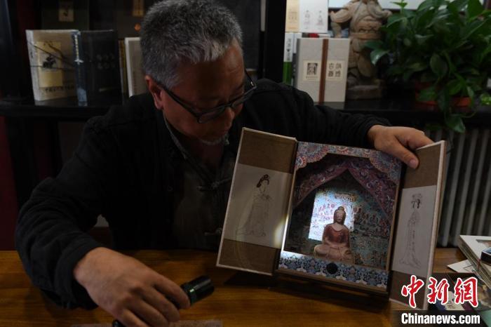 圖為讀者出版集團(tuán)讀者晉林工作室獨(dú)立出品人徐晉林，展示互動(dòng)性強(qiáng)的敦煌題材手工書。(資料圖) 楊艷敏 攝