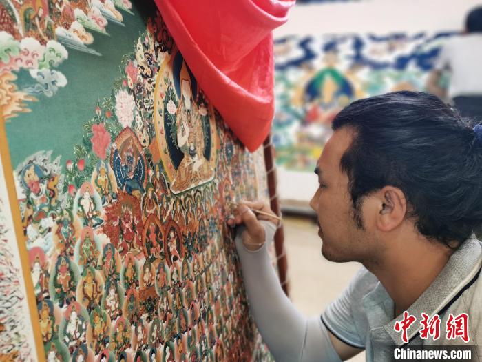 圖為更登才讓的徒弟繪畫(huà)唐卡?！?zhí)砀?攝