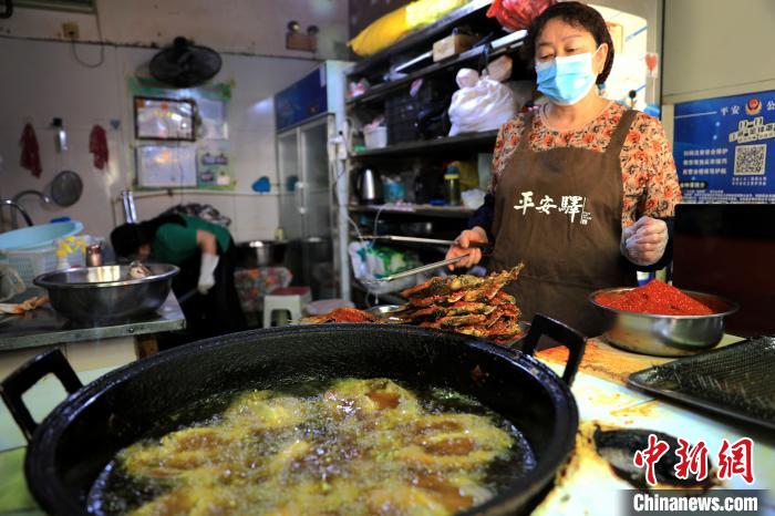 圖為平安驛·河湟民俗文化體驗(yàn)地內(nèi)的商戶(hù)炸干板魚(yú)。　薛蒂 攝